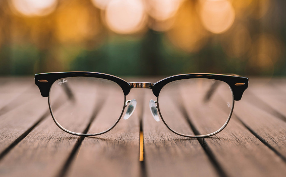 schwarz gerahmte Brille auf braunem Holztisch